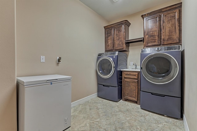 clothes washing area featuring baseboards, washing machine and dryer, a sink, and cabinet space