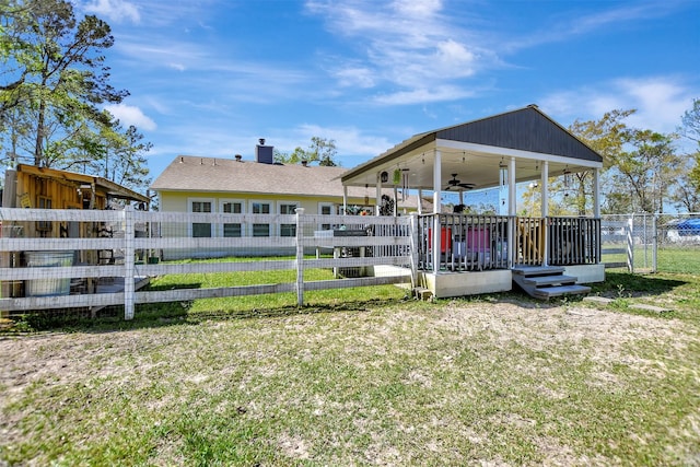 rear view of property featuring a lawn, a chimney, fence, and a ceiling fan