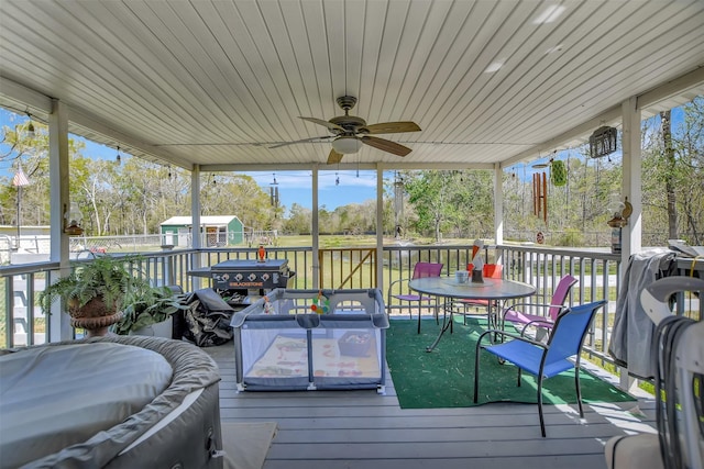 wooden deck featuring ceiling fan, an outbuilding, and a storage unit