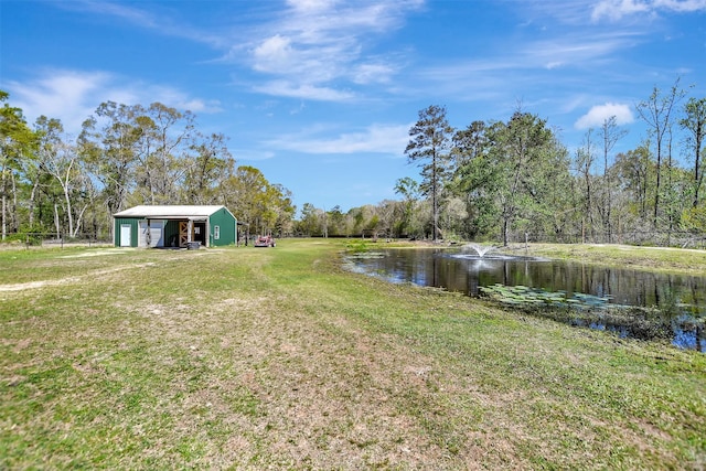 view of yard with a detached garage, an outbuilding, and a water view