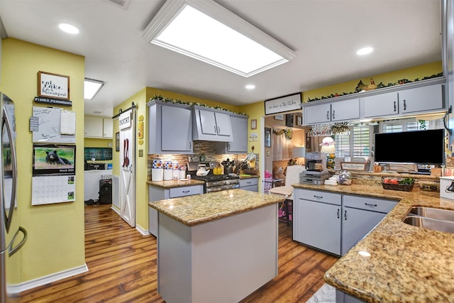 kitchen featuring stainless steel range with gas cooktop, tasteful backsplash, gray cabinetry, and dark wood-type flooring