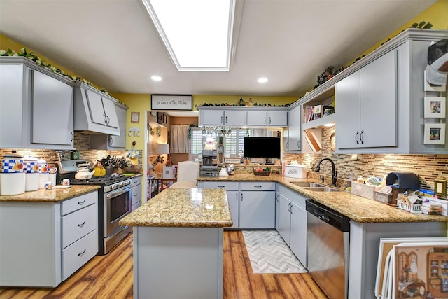 kitchen featuring a sink, light wood-style floors, appliances with stainless steel finishes, and a kitchen island