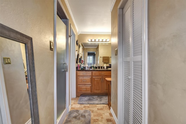 bathroom with a closet, vanity, stone finish flooring, baseboards, and ornamental molding