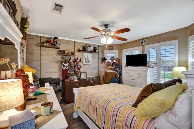 bedroom featuring dark wood-style floors, ceiling fan, brick wall, and visible vents