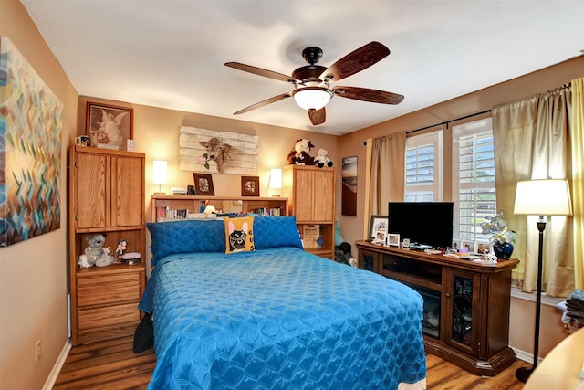 bedroom featuring wood finished floors, a ceiling fan, and baseboards