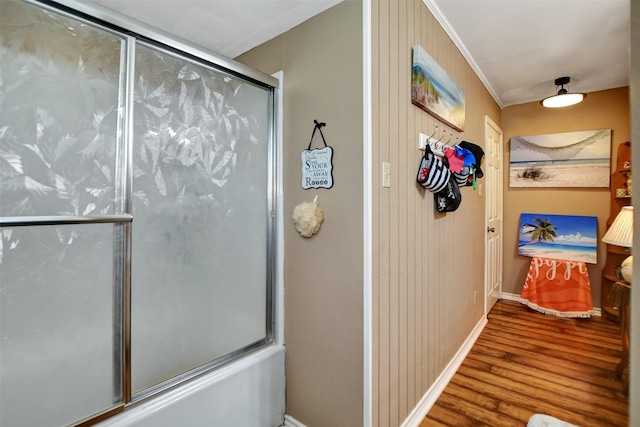 full bathroom with baseboards, bath / shower combo with glass door, and wood finished floors