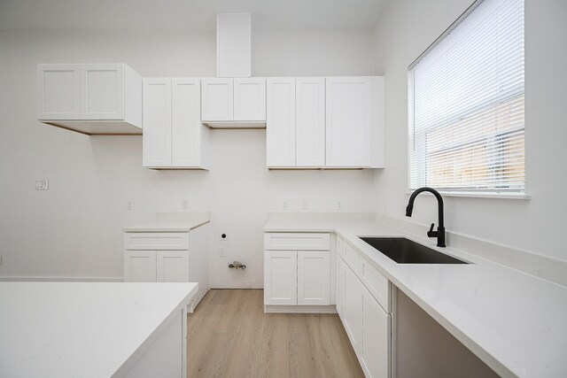 8203 Sparta St Unit B, Houston, TX 77028 - kitchen with light wood finished floors, light countertops, a sink, and white cabinetry