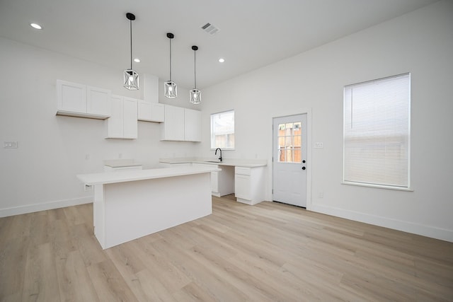 8203 Sparta St Unit B, Houston, TX 77028 - kitchen featuring white cabinets, visible vents, a sink, a center island, and light wood-style flooring