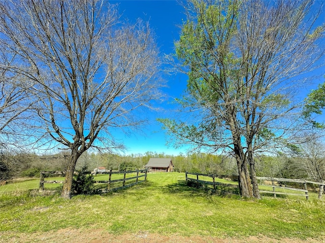 view of yard featuring a rural view, an outbuilding, fence, and an outdoor structure