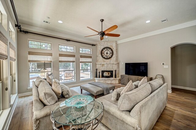 living area with wood finished floors, crown molding, arched walkways, and a ceiling fan