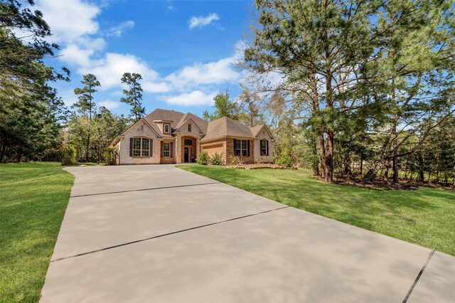 view of front facade featuring a front lawn, driveway, an attached garage, and brick siding