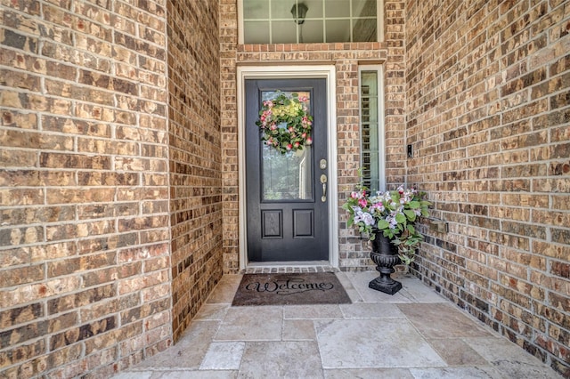 view of exterior entry featuring brick siding