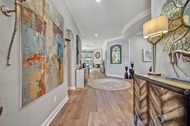 foyer featuring crown molding, baseboards, wood finished floors, recessed lighting, and arched walkways