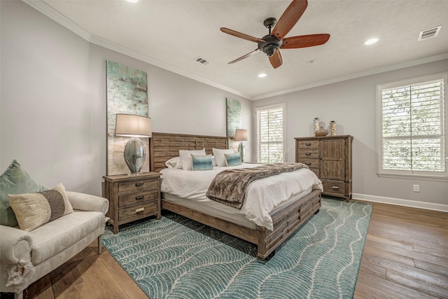 bedroom featuring baseboards, visible vents, crown molding, and wood finished floors