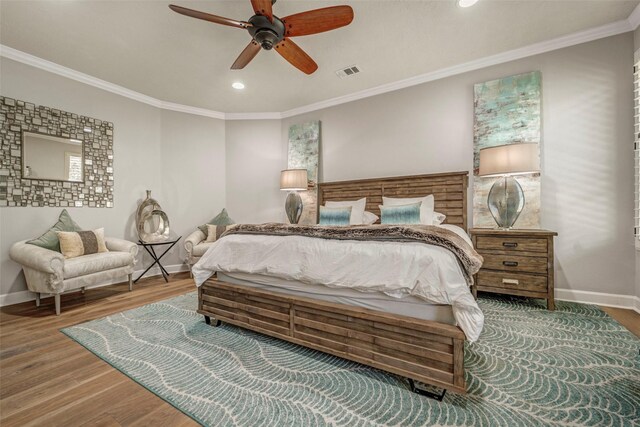 bedroom featuring wood finished floors, ornamental molding, baseboards, and visible vents