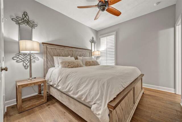 bedroom featuring a ceiling fan, baseboards, and light wood finished floors