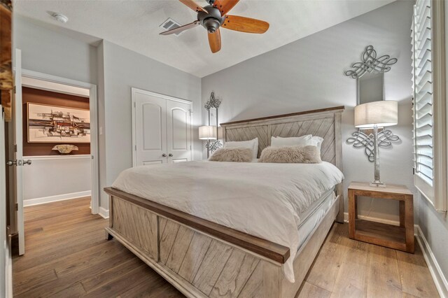 bedroom featuring baseboards, visible vents, wood finished floors, and a closet