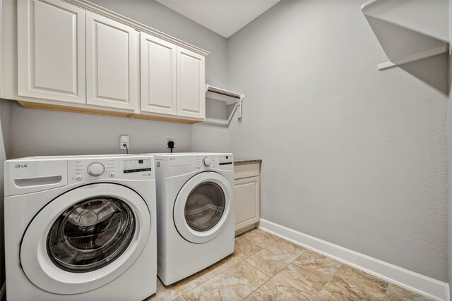 washroom featuring independent washer and dryer, cabinet space, and baseboards