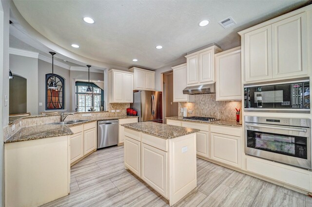 kitchen with under cabinet range hood, a sink, visible vents, a peninsula, and appliances with stainless steel finishes