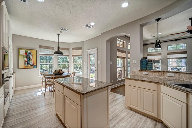 kitchen featuring arched walkways, visible vents, and a healthy amount of sunlight