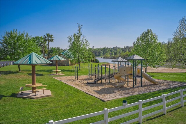communal playground with a lawn, a water view, and fence