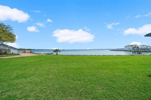 view of green lawn featuring a water view