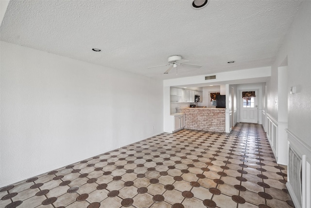 unfurnished living room with ceiling fan and a textured ceiling