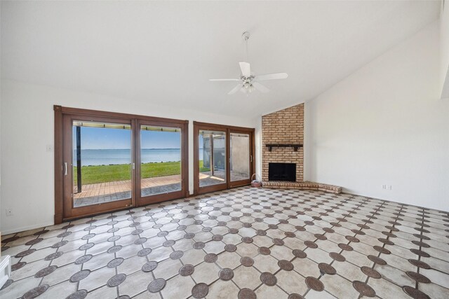 unfurnished living room with lofted ceiling, a water view, ceiling fan, and a fireplace
