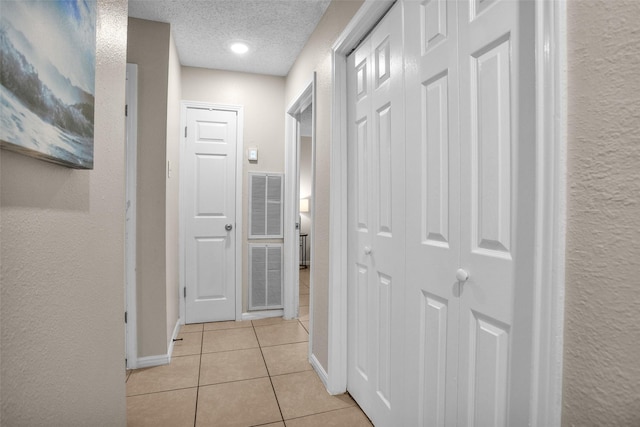 4006 Blalock Rd, Houston, TX 77080 - hallway with baseboards, a textured wall, a textured ceiling, and light tile patterned floors