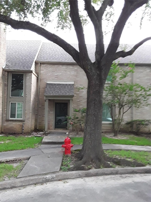 view of front facade with brick siding and a shingled roof