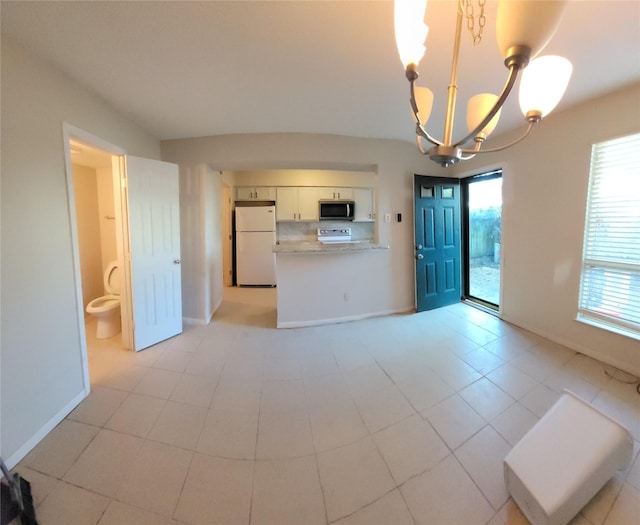 kitchen with baseboards, stainless steel microwave, an inviting chandelier, and freestanding refrigerator
