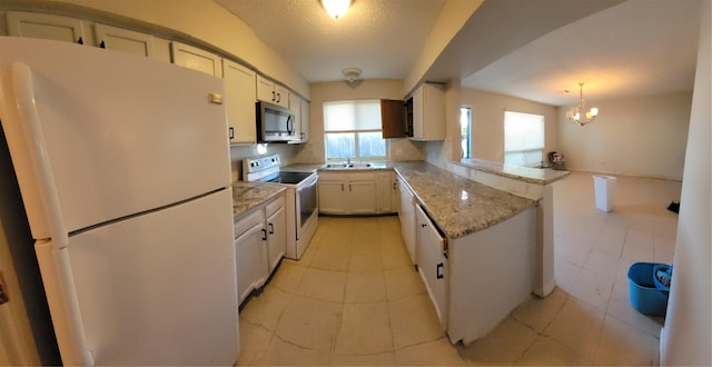 kitchen with a sink, a chandelier, white cabinetry, a peninsula, and white appliances