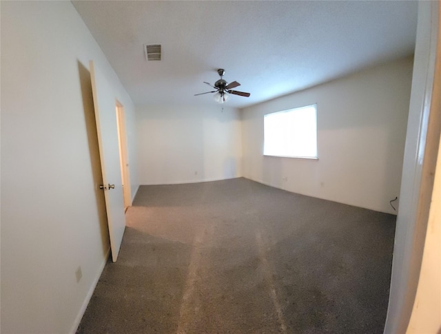 spare room featuring carpet, visible vents, and a ceiling fan