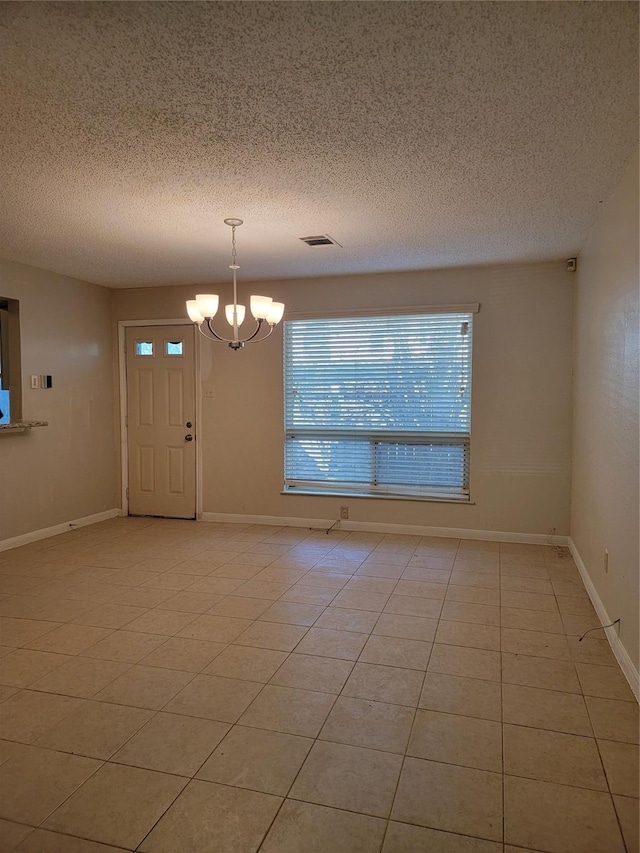 unfurnished room with light tile patterned floors, a textured ceiling, baseboards, and a notable chandelier
