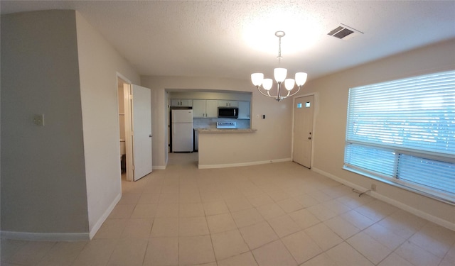 interior space featuring baseboards, visible vents, a textured ceiling, and a chandelier