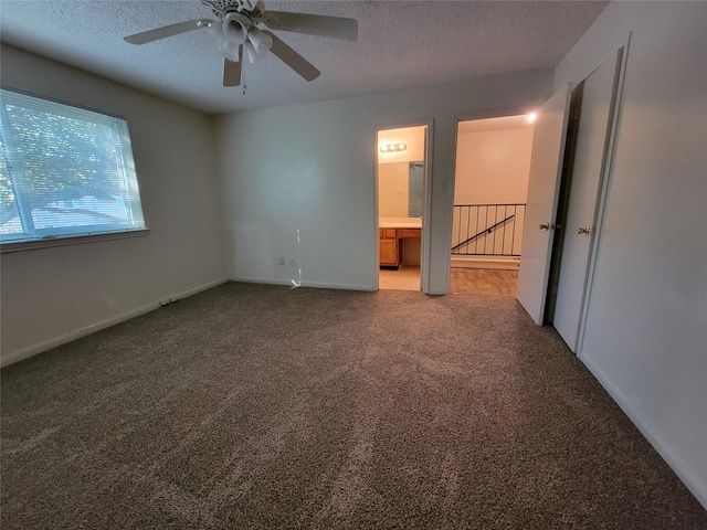 unfurnished bedroom featuring connected bathroom, a textured ceiling, baseboards, ceiling fan, and carpet
