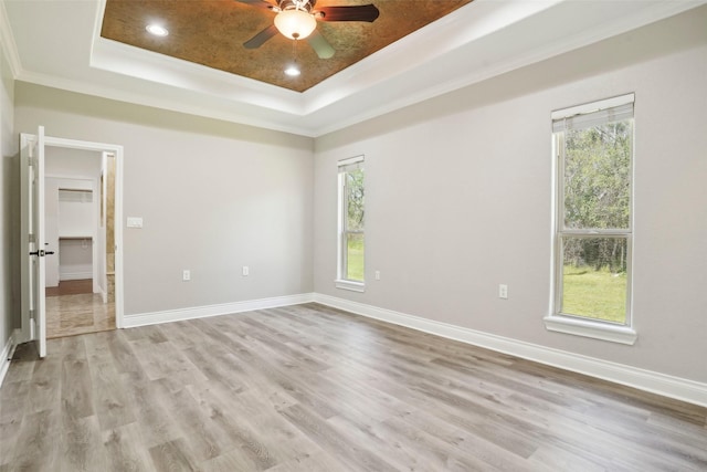 unfurnished bedroom featuring ornamental molding, a raised ceiling, and multiple windows
