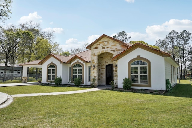 mediterranean / spanish home featuring stucco siding, a front yard, stone siding, and a tile roof