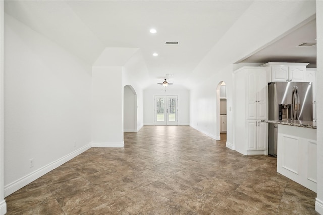 unfurnished living room with arched walkways, visible vents, baseboards, and french doors