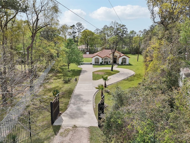surrounding community with a yard, curved driveway, and fence