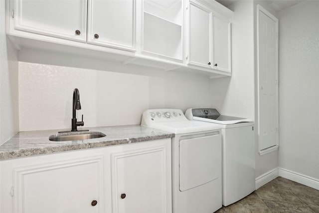 laundry room featuring separate washer and dryer, a sink, cabinet space, and baseboards