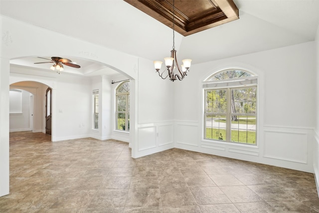 spare room with a decorative wall, a raised ceiling, arched walkways, and ceiling fan with notable chandelier
