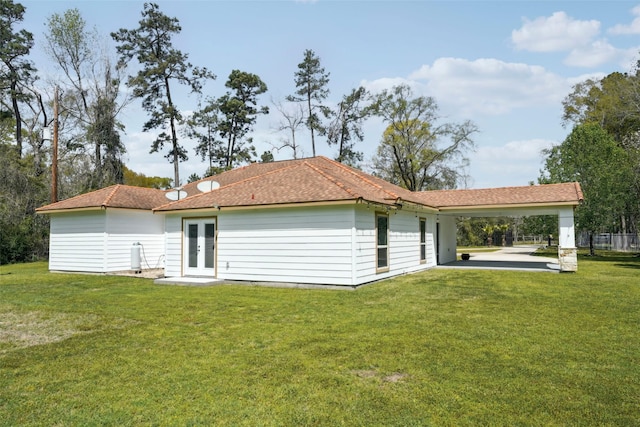 rear view of property featuring a carport, french doors, and a lawn