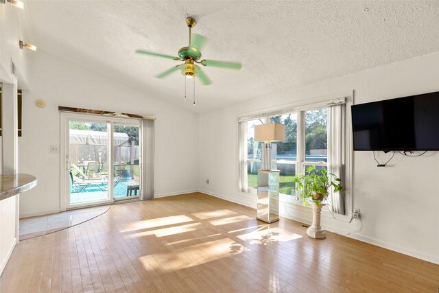 10522 Gulfstream Ln, Sugar Land, TX 77498 - unfurnished living room with light wood-type flooring, a ceiling fan, vaulted ceiling, baseboards, and a textured ceiling