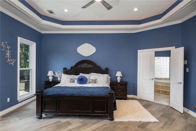 98 Victoria Dr W, Montgomery, TX 77356 - bedroom with ensuite bathroom, visible vents, baseboards, wood finished floors, and a tray ceiling