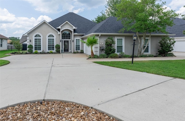 98 Victoria Dr W, Montgomery, TX 77356 - view of front facade featuring stucco siding, a front yard, concrete driveway, and roof with shingles