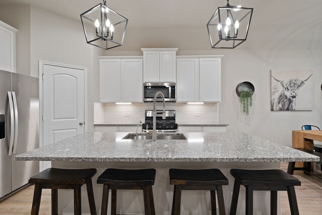 1144 Courteous Creek Dr, Montgomery, TX 77316 - kitchen with stainless steel appliances, a chandelier, backsplash, and light wood-style floors