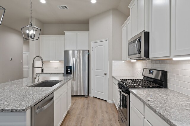 1144 Courteous Creek Dr, Montgomery, TX 77316 - kitchen featuring appliances with stainless steel finishes, a sink, a kitchen island with sink, white cabinets, and recessed lighting