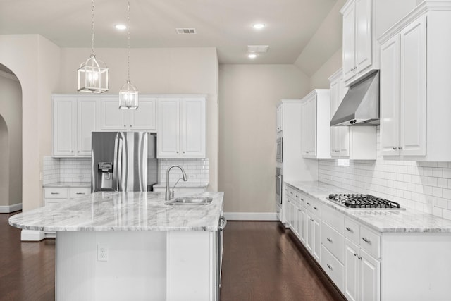 kitchen with dark wood-style floors, stainless steel appliances, arched walkways, a sink, and ventilation hood