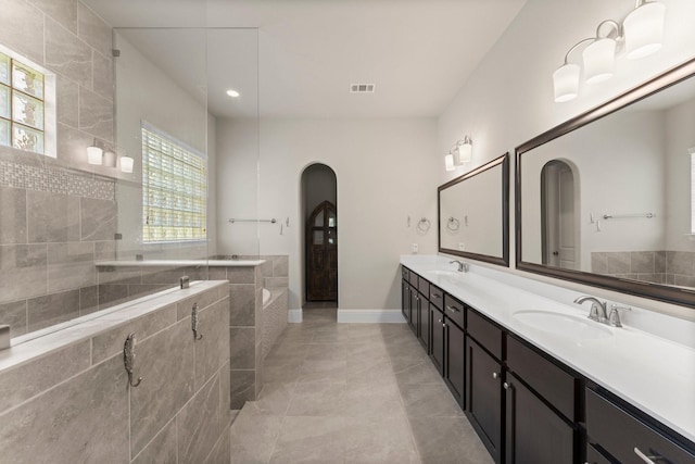 full bathroom with a garden tub, double vanity, a sink, and visible vents